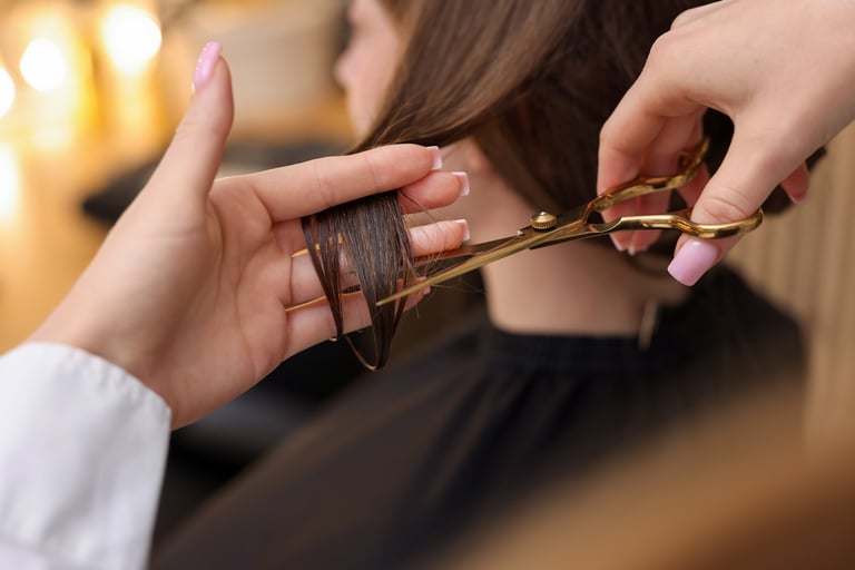Hairstylist cutting client's hair with scissors
