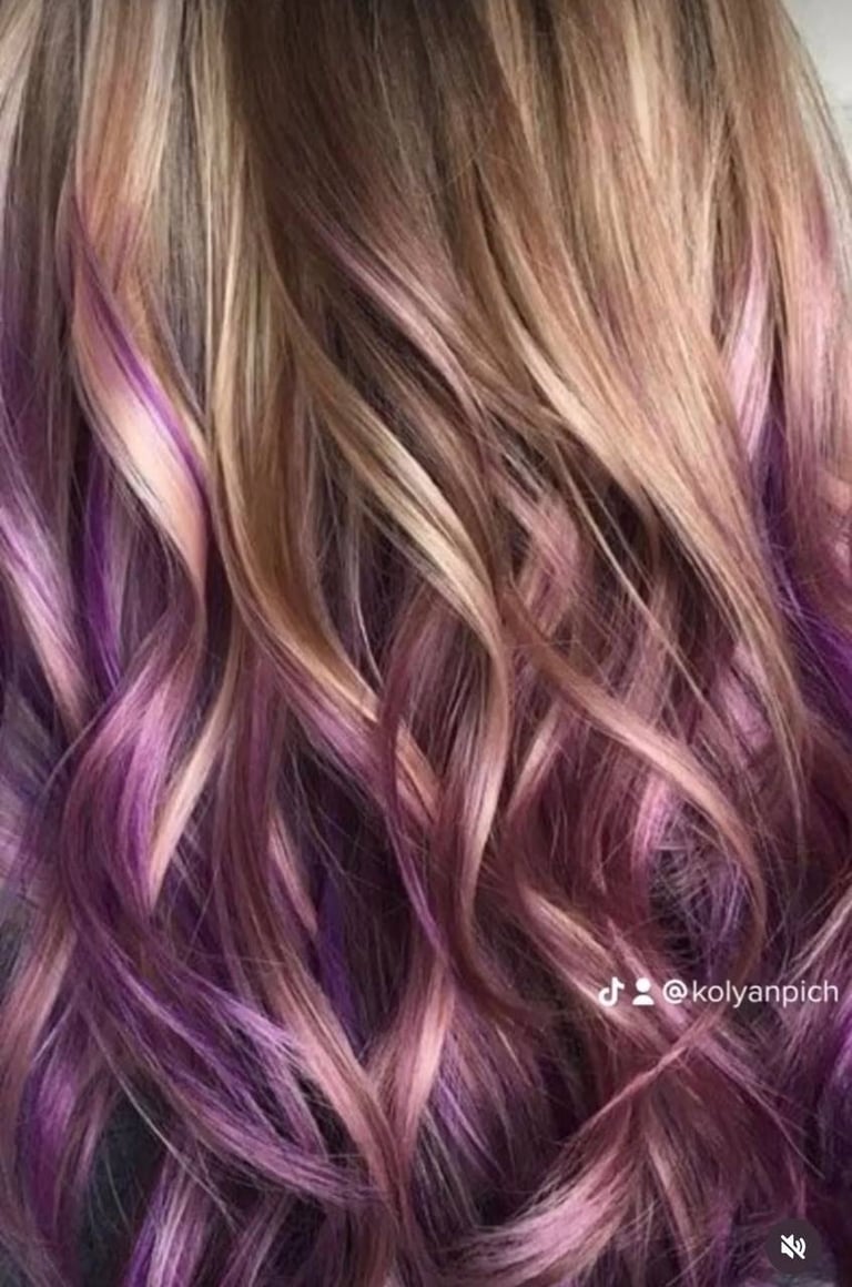 Long wavy hair with ombre color blending from brown and blonde at the roots to vibrant purple and pink tones at the ends