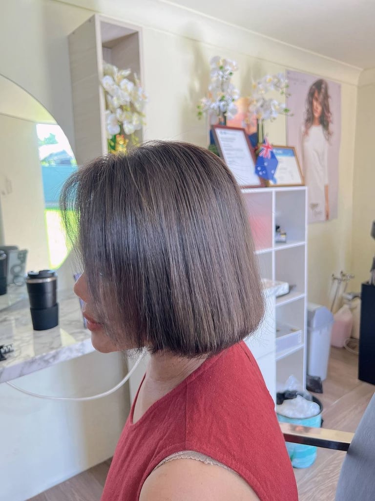 Woman with shoulder-length dark hair wearing a red shirt viewed from behind in a bedroom with vanity mirror and shelving