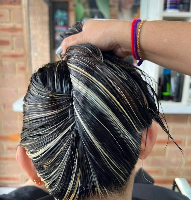 Back view of woman with black hair and silver highlights styled in a sleek bun, wearing a colorful bracelet