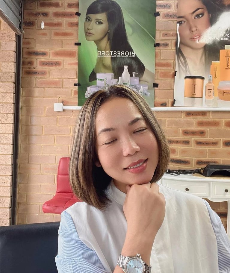 Woman with shoulder-length hair smiling at camera in beauty salon with cosmetic product displays and brick walls