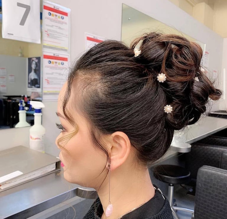 Side profile of woman with dark hair styled in an updo with white hair clips in a salon setting