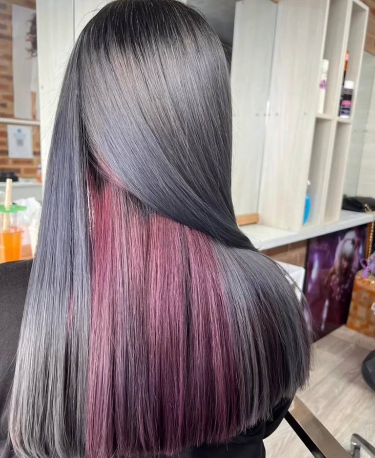 Back view of person with long gray hair featuring a hidden pink and burgundy underlayer revealed as hair falls over shoulder